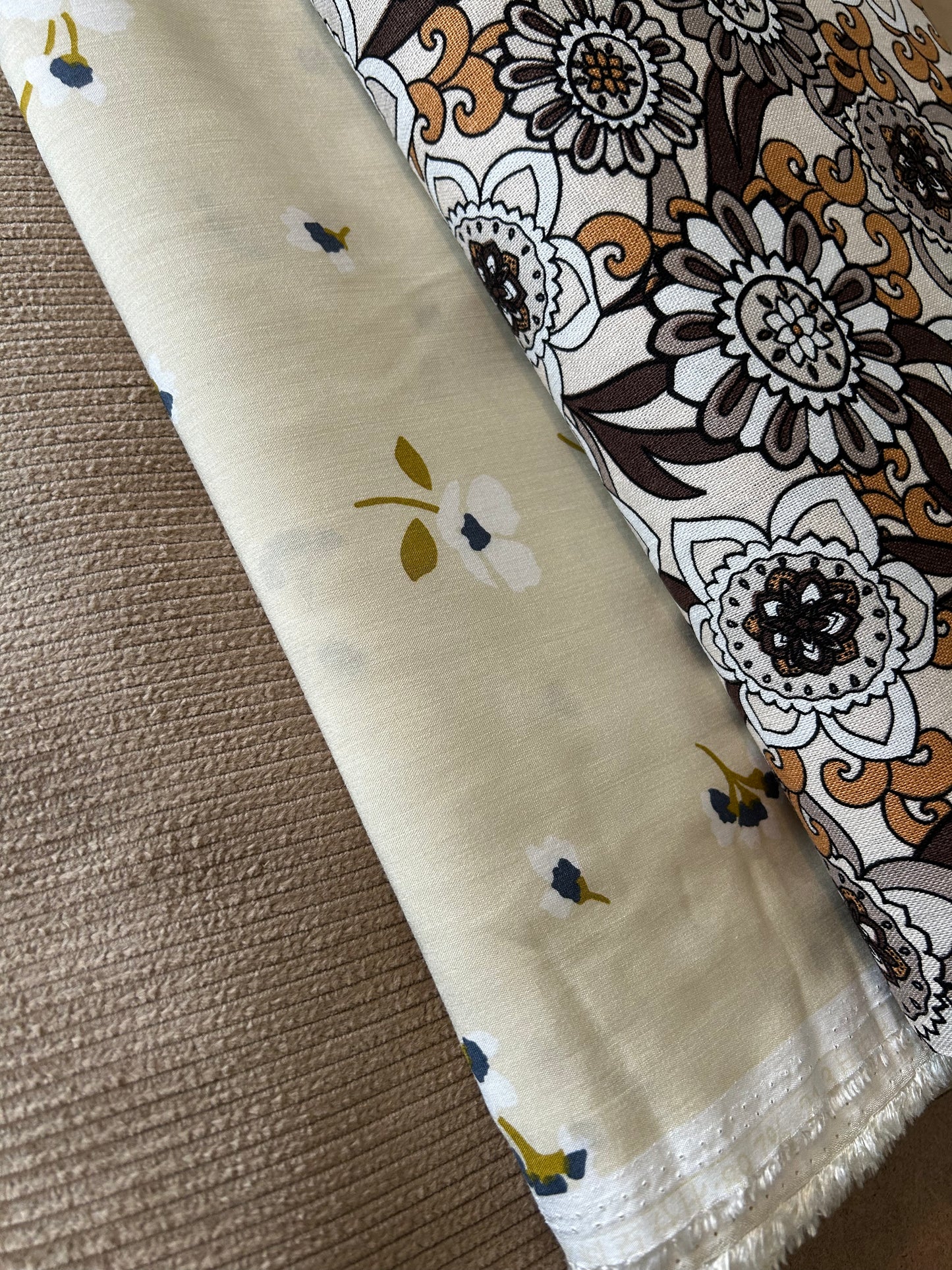Two fabric swatches with floral patterns on a textured surface